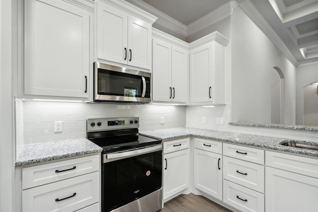 kitchen with white cabinets, light stone counters, crown molding, and appliances with stainless steel finishes