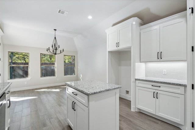 kitchen featuring light stone countertops, light wood-type flooring, and white cabinetry