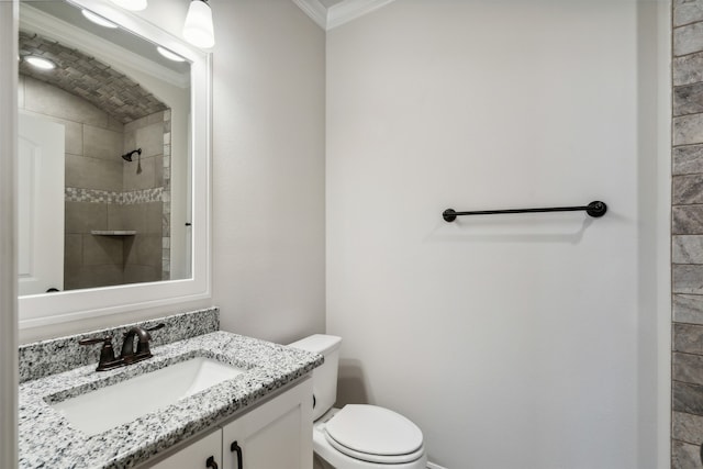 bathroom featuring vanity, toilet, ornamental molding, and tiled shower