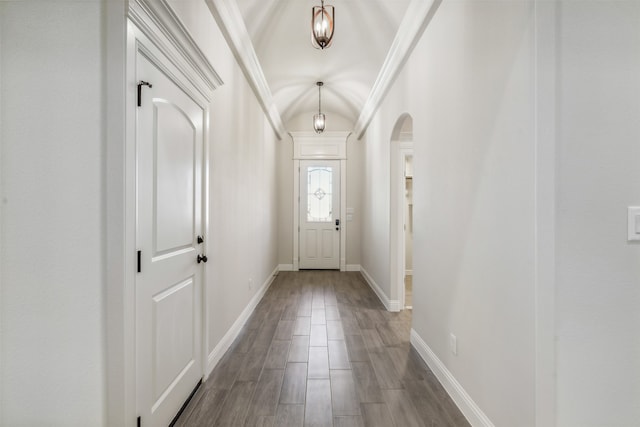 doorway with hardwood / wood-style floors, lofted ceiling, and ornamental molding