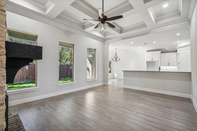 unfurnished living room with beam ceiling, ceiling fan, coffered ceiling, crown molding, and light wood-type flooring