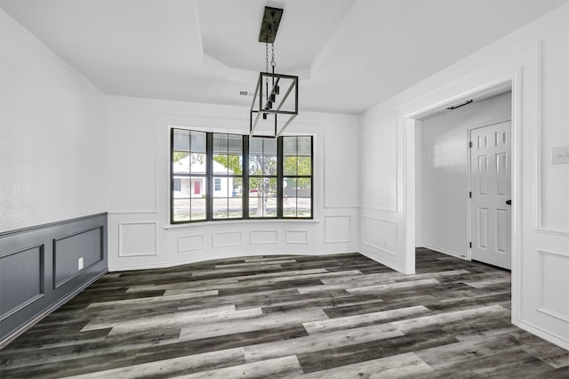 608 N Ave, Whitesboro, TX 76273 - unfurnished dining area featuring a chandelier, a raised ceiling, a decorative wall, dark wood finished floors, and a wainscoted wall