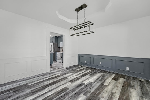 unfurnished dining area with a raised ceiling and dark hardwood / wood-style flooring