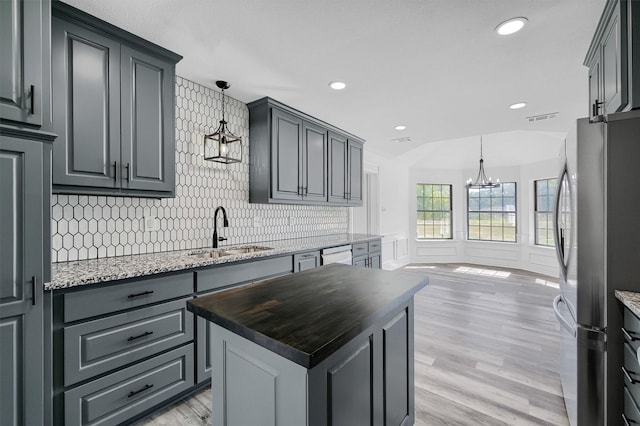 kitchen featuring a center island, hanging light fixtures, sink, and stainless steel fridge