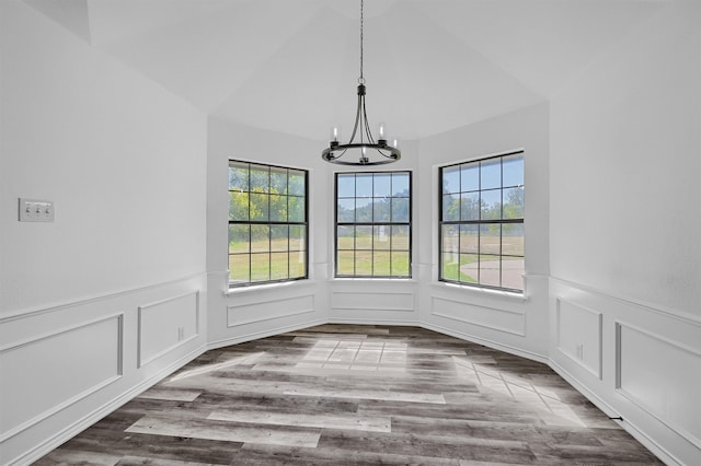 unfurnished dining area with lofted ceiling, a notable chandelier, and wood-type flooring