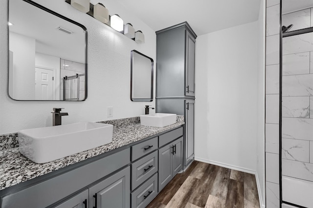 bathroom with vanity, hardwood / wood-style floors, and tiled shower