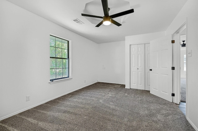 unfurnished bedroom with dark colored carpet, a closet, and ceiling fan