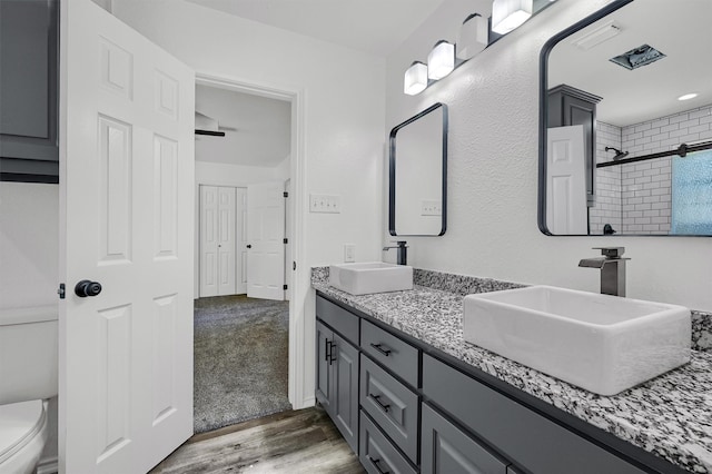 bathroom featuring vanity, hardwood / wood-style floors, toilet, and a tile shower