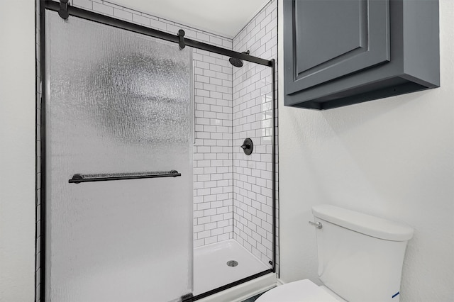 bathroom featuring toilet and a shower with shower door