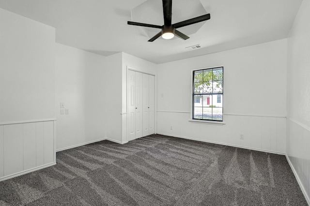 608 N Ave, Whitesboro, TX 76273 - unfurnished bedroom featuring dark carpet, ceiling fan, a closet, and a wainscoted wall