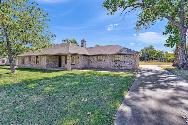 608 N Ave, Whitesboro, TX 76273 - view of front of house with brick siding, a front yard, a chimney, and driveway