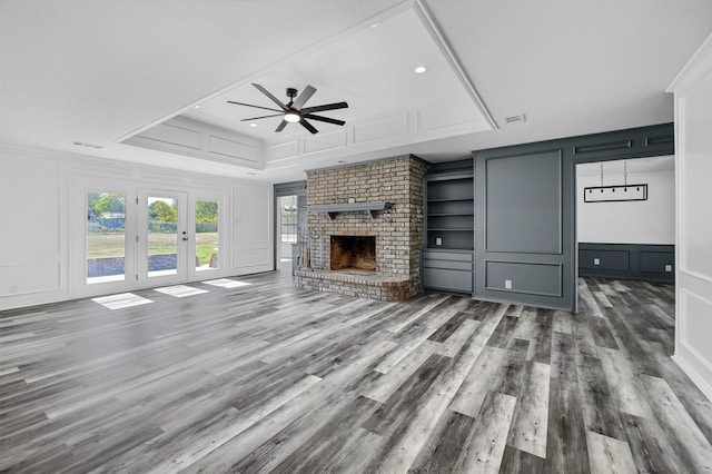 unfurnished living room with dark hardwood / wood-style floors, a raised ceiling, a fireplace, and ceiling fan