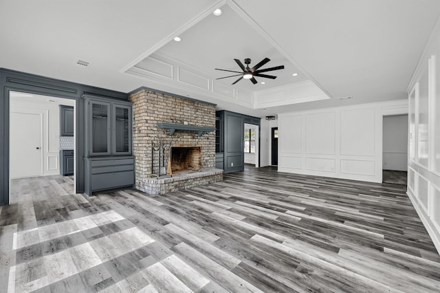 unfurnished living room featuring ornamental molding, dark hardwood / wood-style floors, a fireplace, and ceiling fan