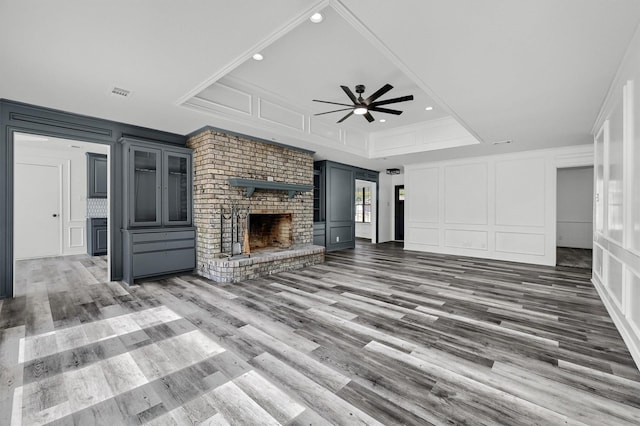 608 N Ave, Whitesboro, TX 76273 - unfurnished living room featuring a decorative wall, a ceiling fan, a fireplace, wood finished floors, and recessed lighting