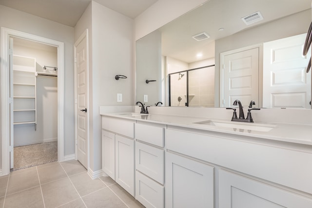 bathroom featuring a shower with door, vanity, and tile patterned floors