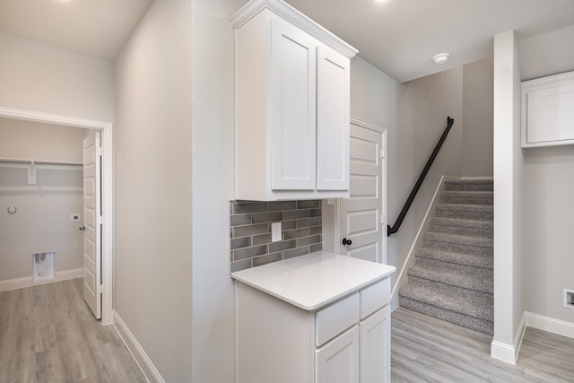 kitchen with decorative backsplash, white cabinets, and light wood-type flooring