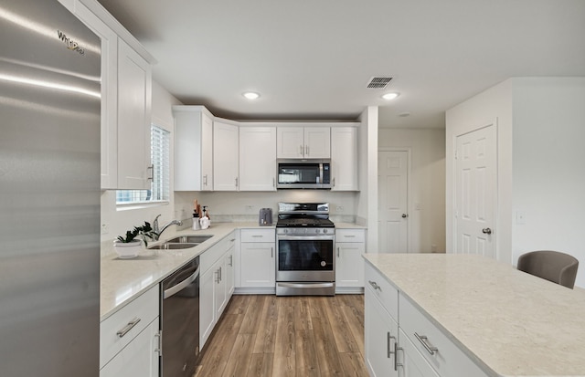 kitchen featuring dark hardwood / wood-style flooring, white cabinetry, light stone countertops, sink, and stainless steel appliances