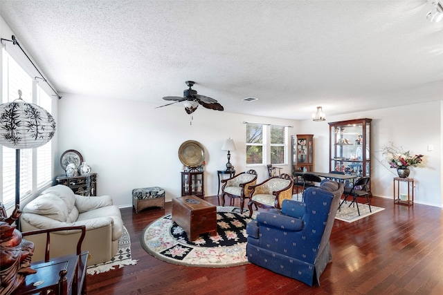 living room with dark hardwood / wood-style flooring, a textured ceiling, and ceiling fan