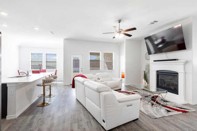 living room with ceiling fan, sink, and light hardwood / wood-style floors