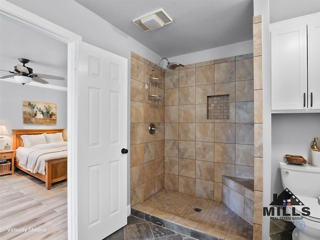 bathroom with ceiling fan, toilet, and a tile shower