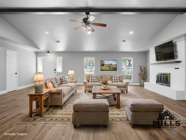 living room with vaulted ceiling, a brick fireplace, ceiling fan, and light hardwood / wood-style floors