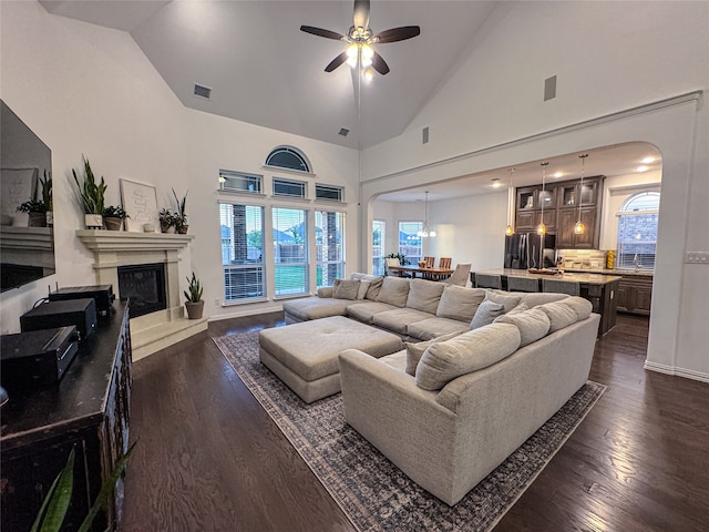 living room featuring dark hardwood / wood-style floors, high vaulted ceiling, and ceiling fan