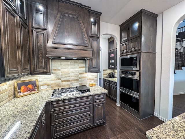 kitchen featuring light stone countertops, appliances with stainless steel finishes, premium range hood, and dark hardwood / wood-style floors