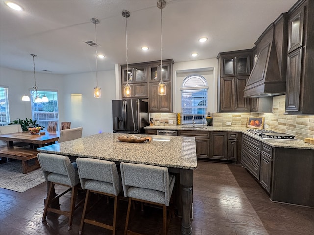 kitchen with dark brown cabinets, appliances with stainless steel finishes, a center island, and dark hardwood / wood-style floors