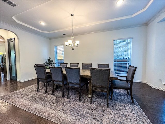 dining area featuring ornamental molding, a notable chandelier, a tray ceiling, and dark hardwood / wood-style flooring