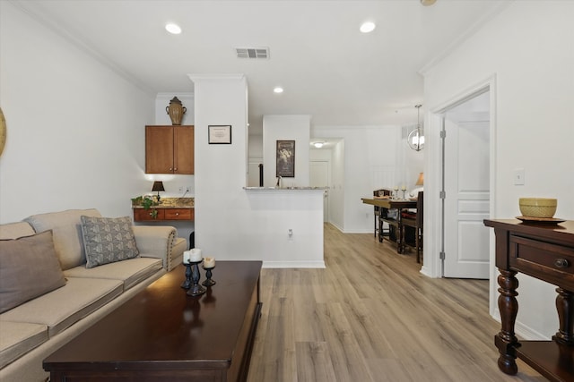 living room with crown molding, light hardwood / wood-style flooring, and a chandelier