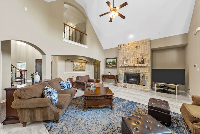 living room featuring high vaulted ceiling, light hardwood / wood-style floors, ceiling fan, and a fireplace