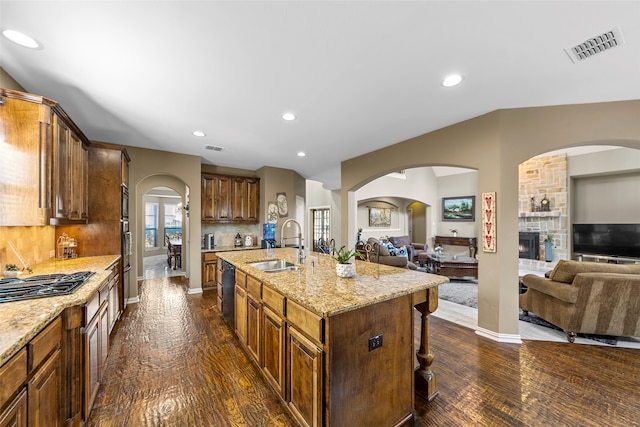 kitchen with a center island with sink, sink, tasteful backsplash, black refrigerator with ice dispenser, and dark hardwood / wood-style floors