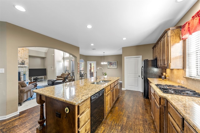 kitchen with stainless steel appliances, sink, an island with sink, a breakfast bar area, and dark wood-type flooring