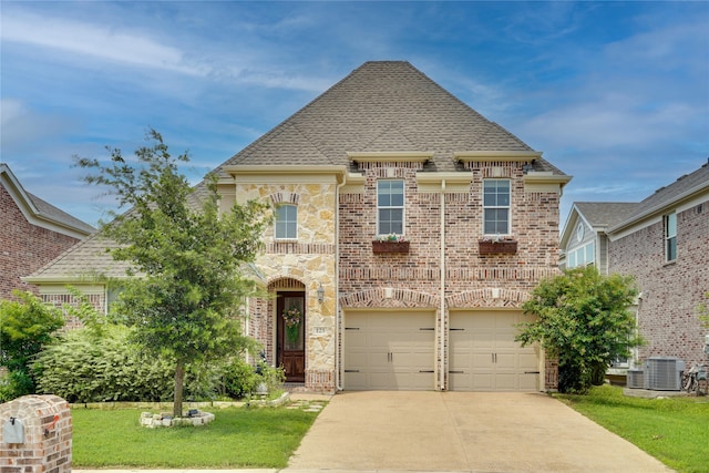 view of front of property featuring a front yard, central AC, and a garage