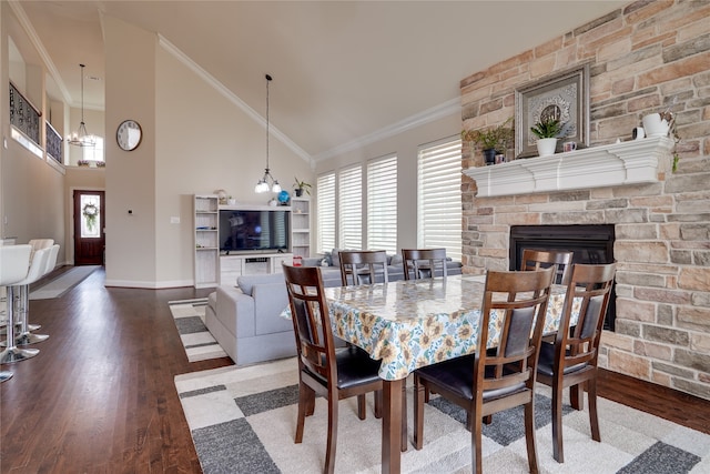 dining area with ornamental molding, a fireplace, a notable chandelier, and wood-type flooring