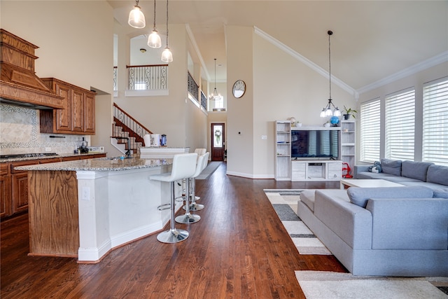 kitchen with light stone countertops, a kitchen breakfast bar, decorative light fixtures, gas stovetop, and dark hardwood / wood-style floors