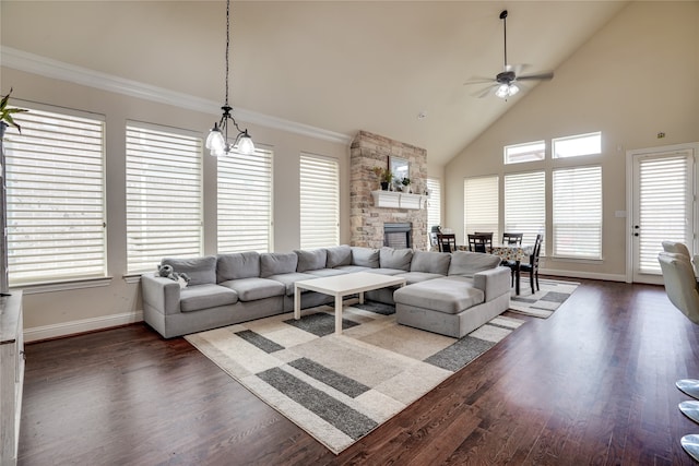 living room featuring a fireplace, ceiling fan with notable chandelier, dark wood-type flooring, high vaulted ceiling, and ornamental molding