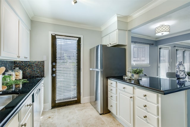 kitchen featuring stainless steel fridge, a wealth of natural light, decorative backsplash, and white cabinets