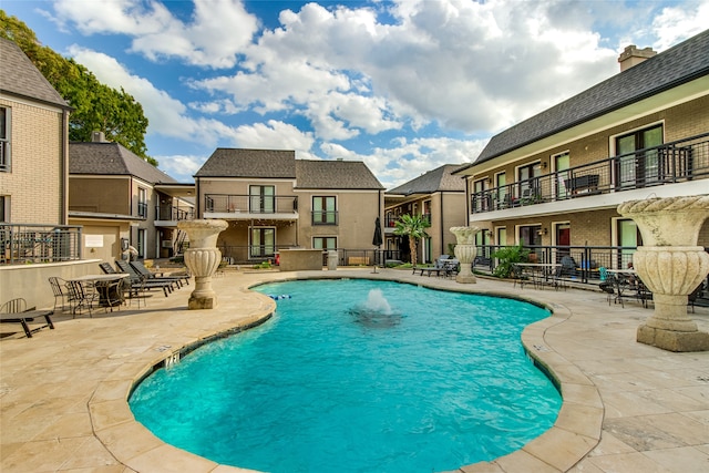 view of swimming pool with pool water feature and a patio