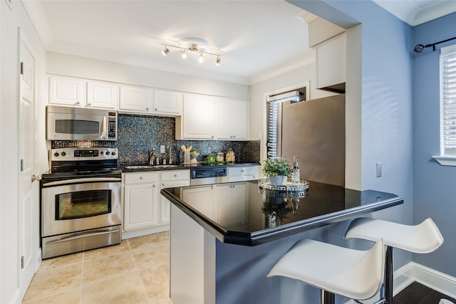 kitchen featuring a kitchen bar, kitchen peninsula, stainless steel appliances, and white cabinets