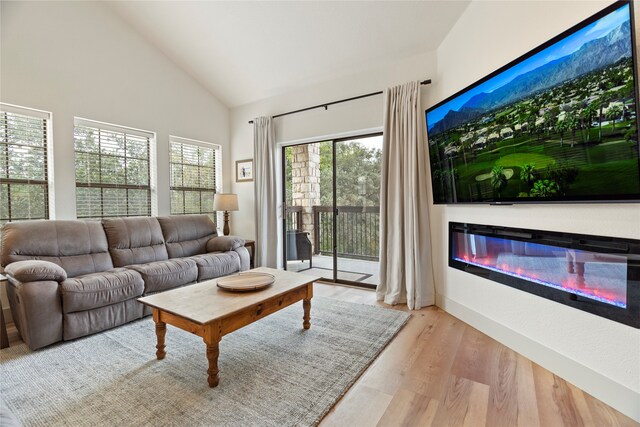 living room with high vaulted ceiling and light hardwood / wood-style floors