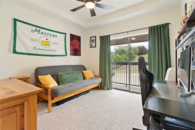 office space with carpet, ceiling fan, and a tray ceiling