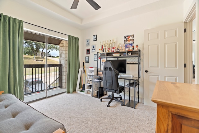 office space with a tray ceiling, light colored carpet, and ceiling fan