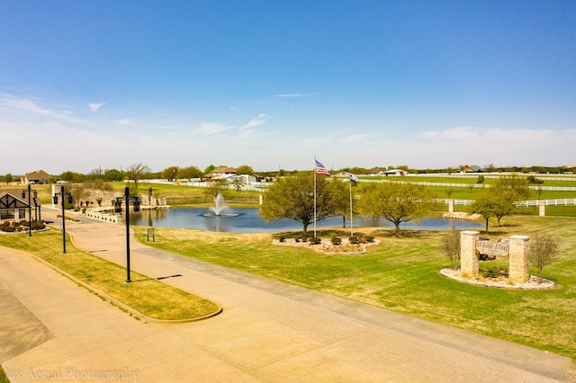 view of property's community with a water view and a lawn