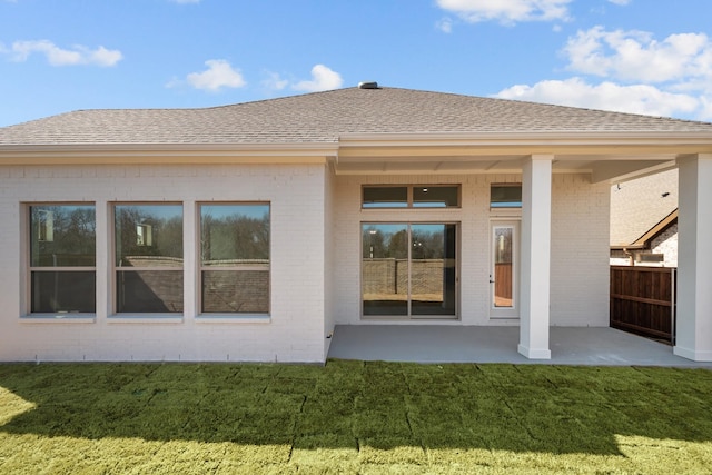 back of house with brick siding, a yard, a patio, a shingled roof, and fence