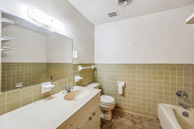 bathroom featuring tile walls, vanity, a tub, and toilet