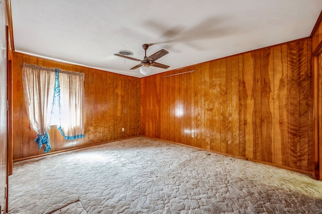 spare room with wood walls, light colored carpet, and ceiling fan