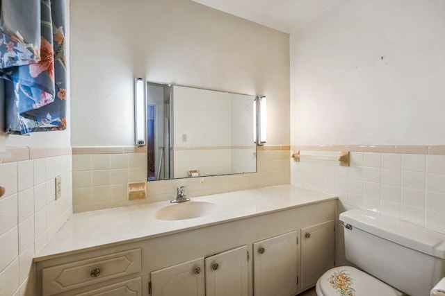 bathroom featuring toilet, vanity, and tile walls