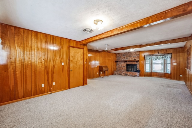 unfurnished living room featuring a fireplace, wood walls, and carpet