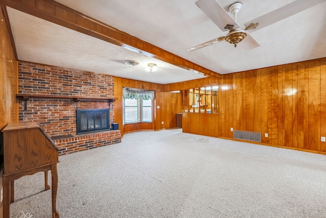 unfurnished living room featuring wooden walls, a fireplace, a textured ceiling, and carpet floors